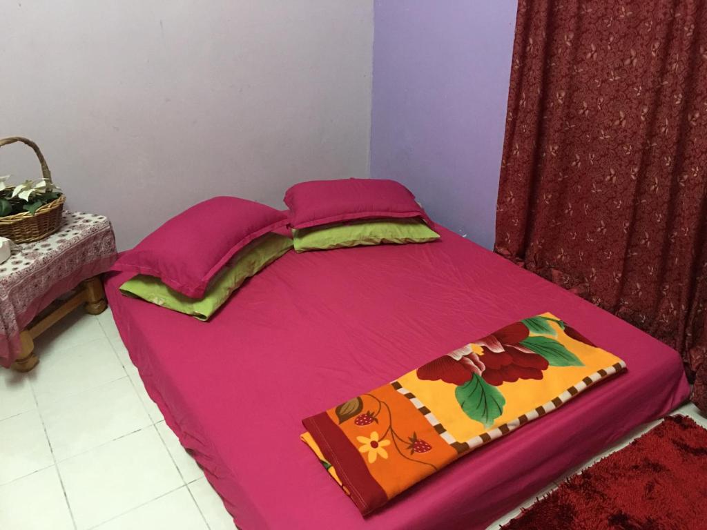 a bed with a pink sheets and a blanket at Homestay Teratak Saazlina in Seremban