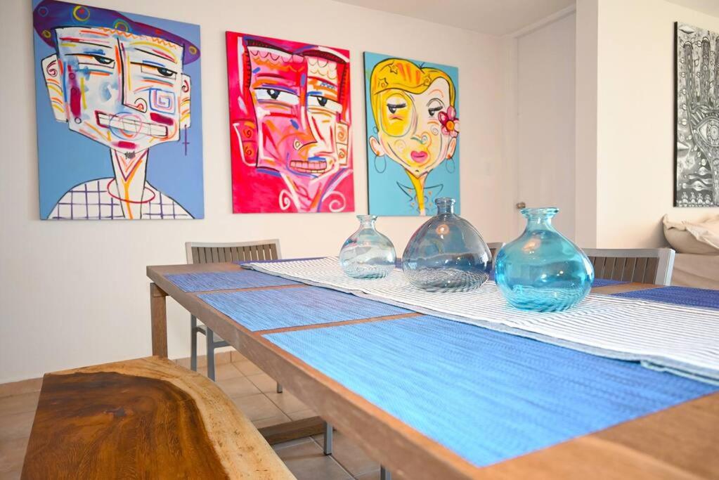 a table with four glass vases on it with paintings at New Remodeled Ocean view, Beach Front Apartment in Arecibo