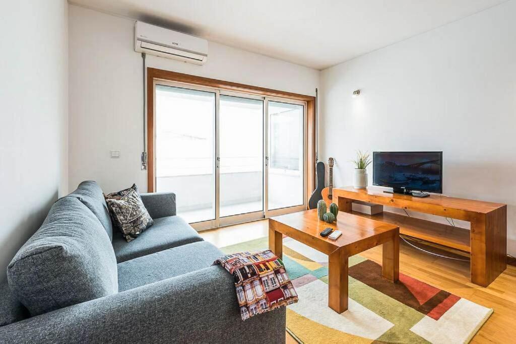 een woonkamer met een blauwe bank en een tafel bij Loulé 246 · 1 bedroom apartment · Parking in Porto