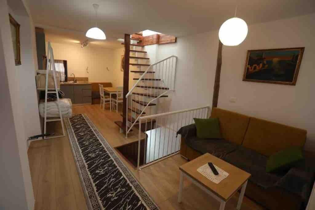 a living room with a couch and a spiral staircase at Charming House in Pogradec