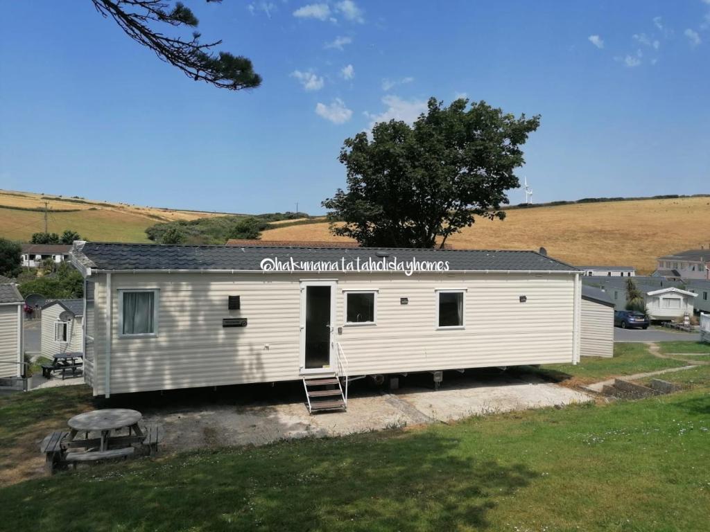 a small white house with a tree on the side of it at Hakuna Matata Holiday Homes - Newquay Bay Resort in Newquay