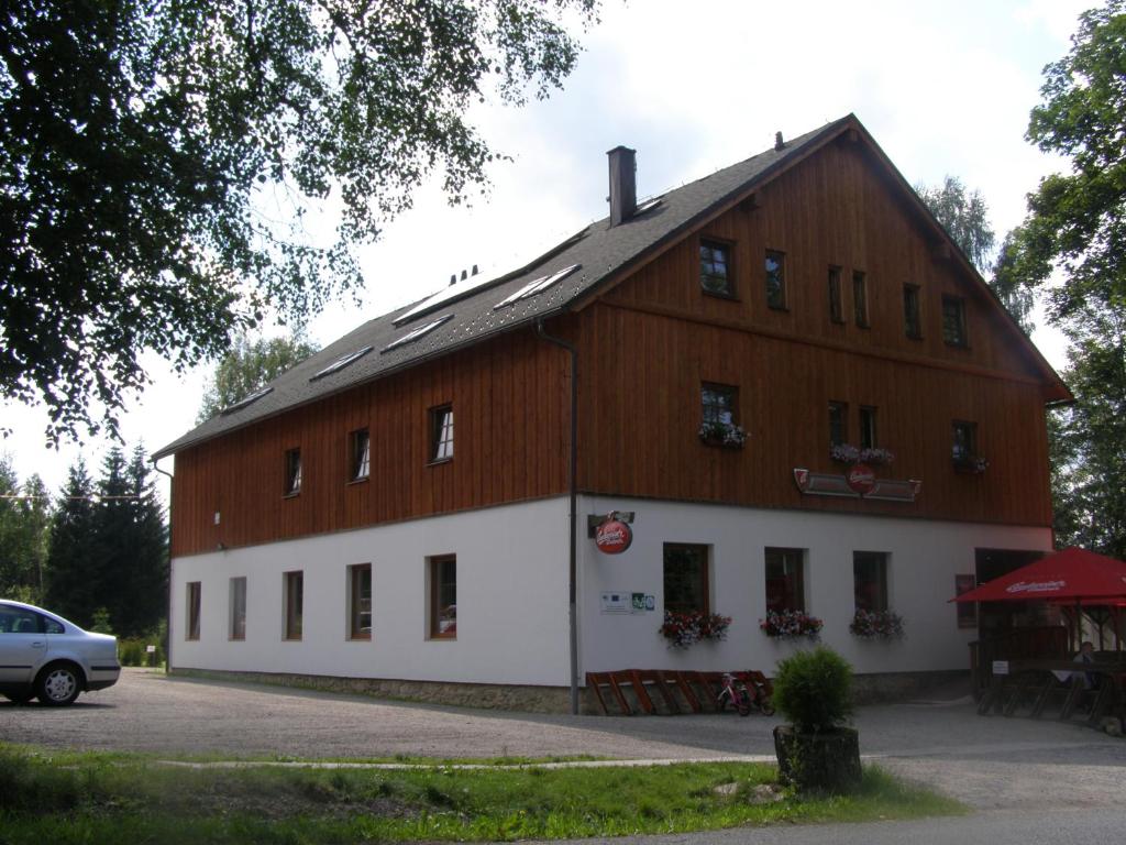 a large white building with a wooden roof at Wellness Hotel Marlin in Nová Pec
