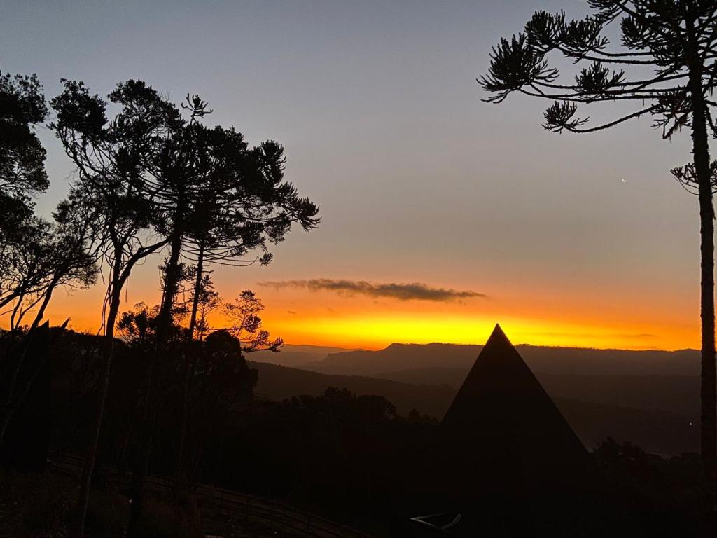 a sunset in the mountains with a pyramid in the foreground at Cabanas Cold Mountain in Urubici