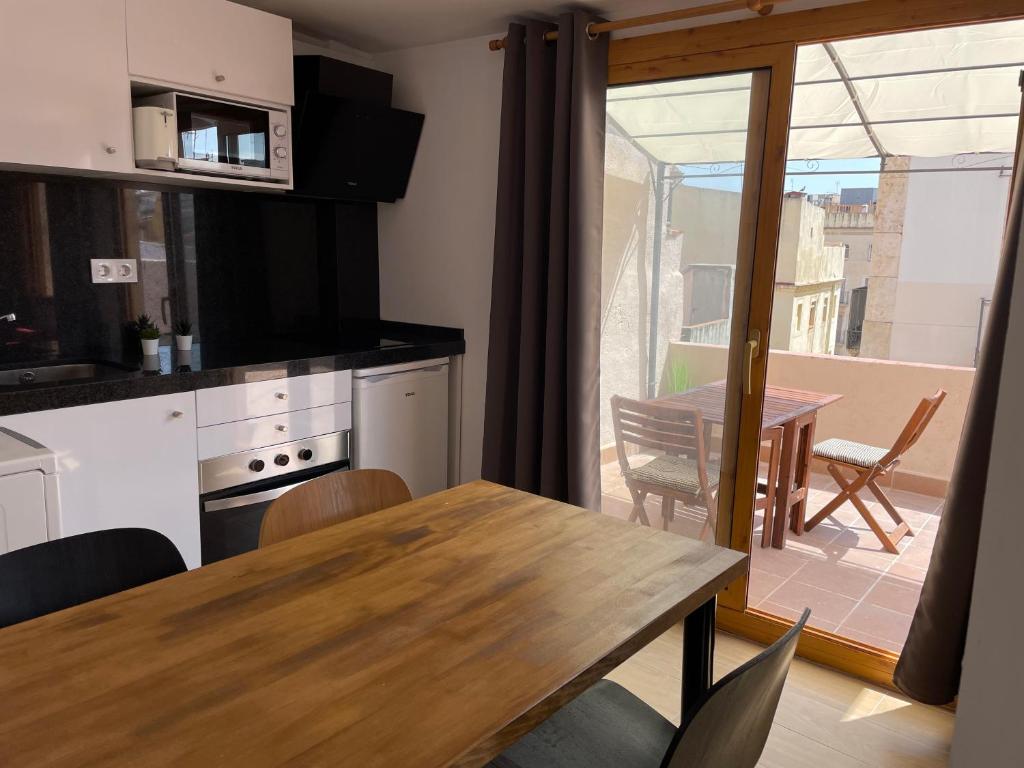 eine Küche und ein Esszimmer mit einem Tisch und einem Balkon in der Unterkunft Casa Ferrers piso 5. Precioso ático con terraza in Tarragona