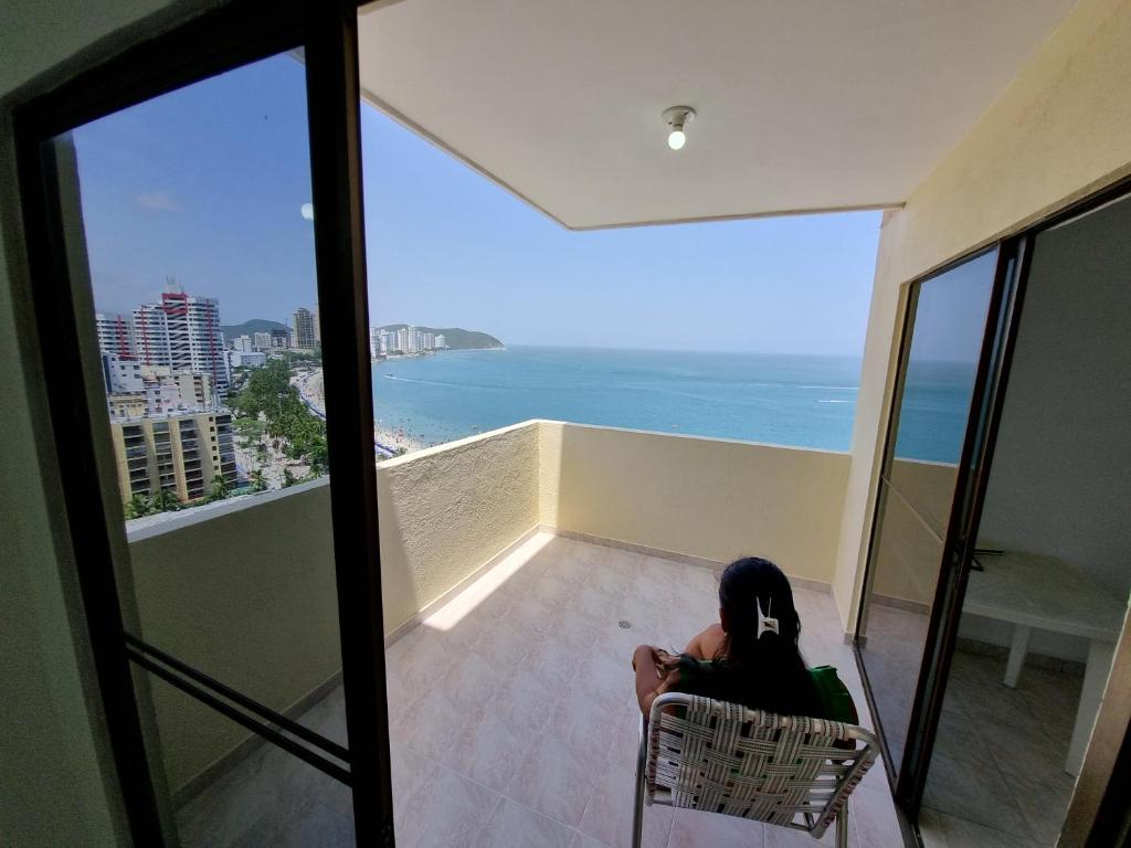 a woman sitting in a chair looking out at the ocean at Apartamento Santa Marta Laureles 16 by reservastodo in Gaira