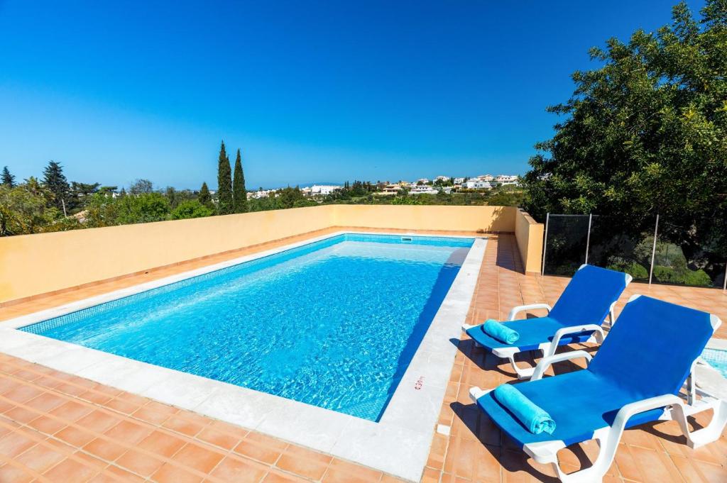 una piscina con 2 sillas azules y una piscina en Villa Miranda by Villa Plus, en Albufeira