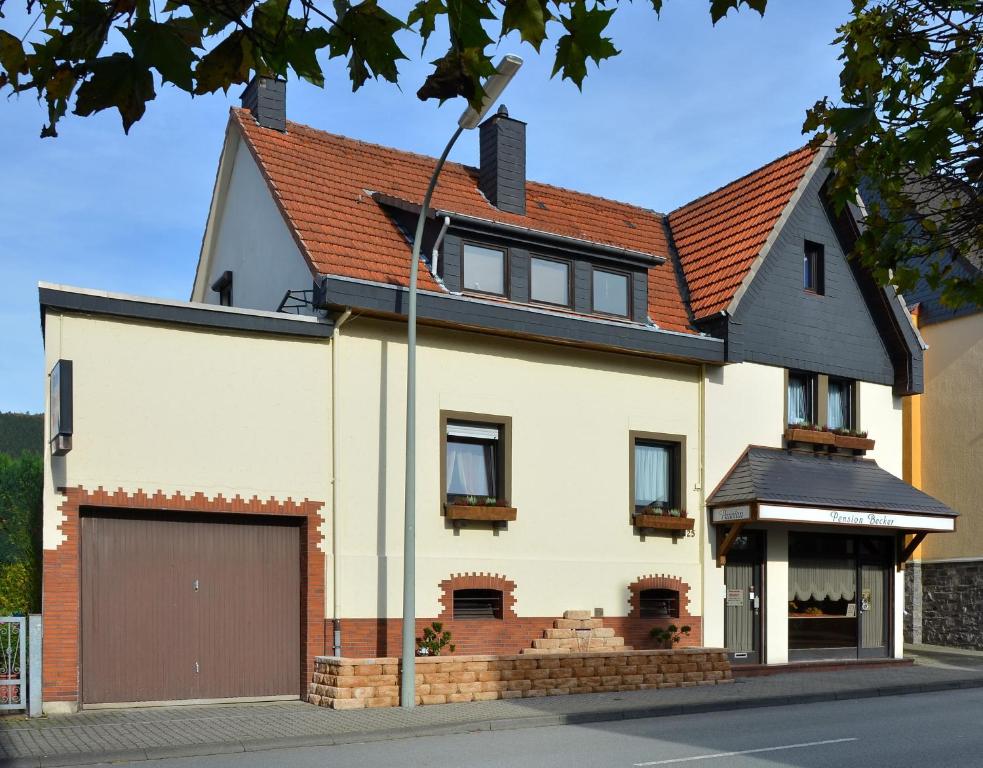 a white house with a brown roof and a garage at Pension Becker in Arnsberg