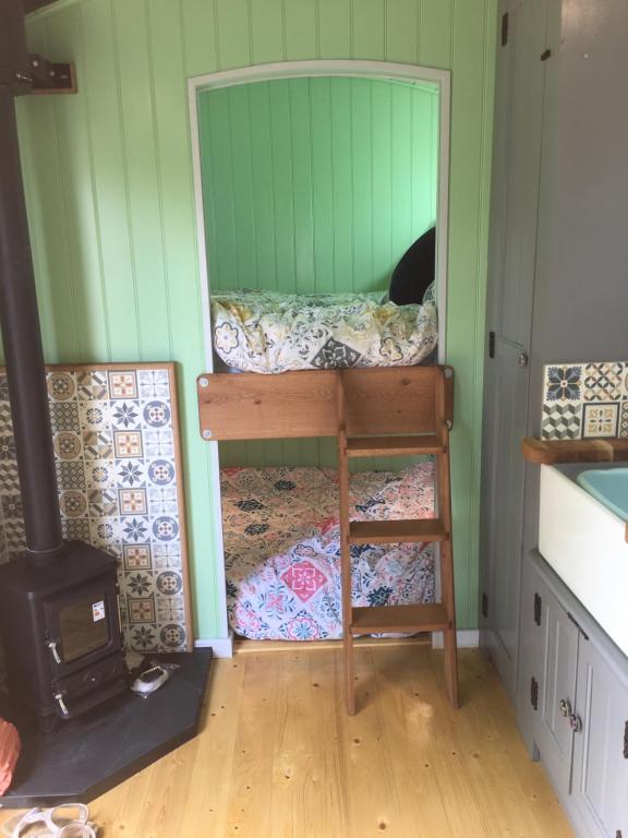 a room with a bunk bed and a stove at Jasmine The Shepherd Hut in Woodhall Spa