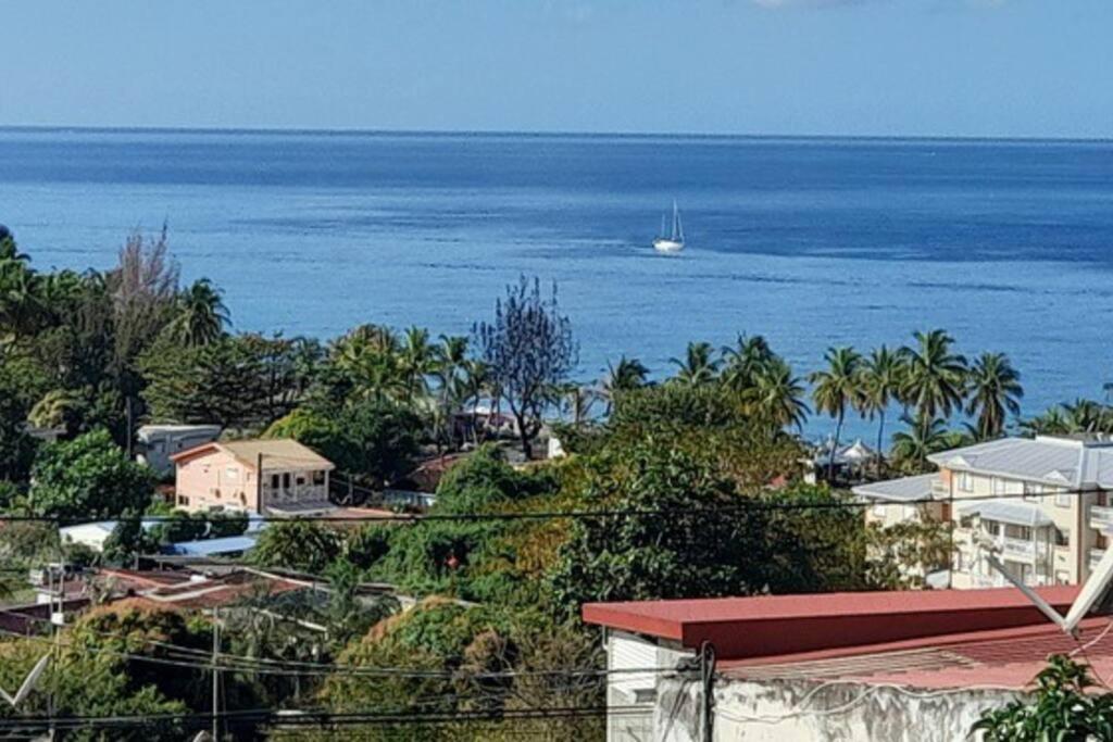 una vista del océano con un barco a lo lejos en Evasion Nord Caraïbe vue mer -plage 5 mn à pieds en Le Carbet