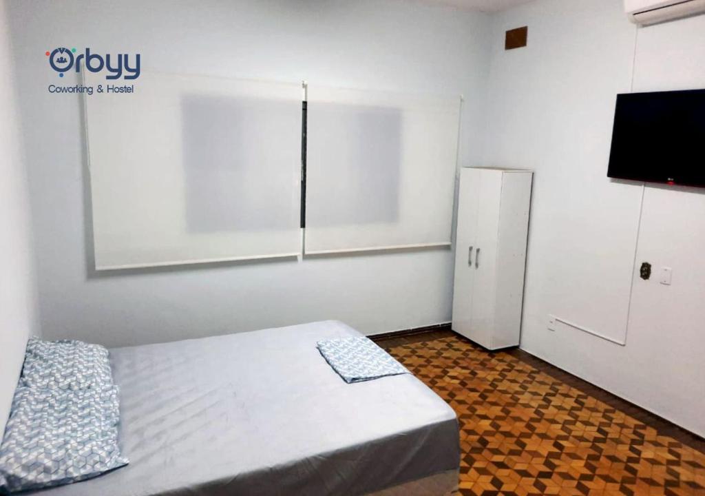 um pequeno quarto com uma cama e um frigorífico em Ritz Hostel em Araçatuba