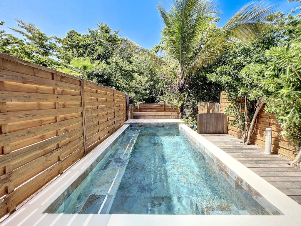 an infinity pool in a backyard with a wooden fence at Villa Ti Bo Beach, a few steps away from the beach, private pool in Orient Bay