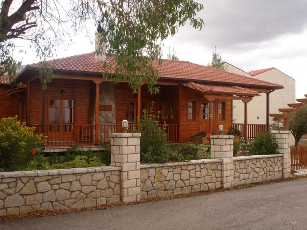 a wooden house with a stone fence in front of it at Xylino Chalet in Kalavrita