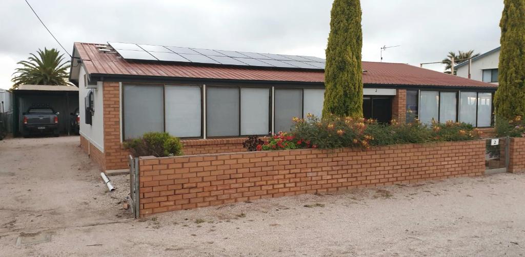 ein Haus mit einer Ziegelwand mit Sonnenkollektoren darauf in der Unterkunft Smoky Bay Holiday Home in Smoky Bay
