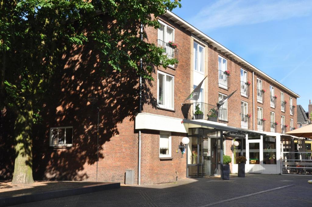 un edificio de ladrillo con un árbol delante de él en Stadshotel de Graafschap en Doetinchem