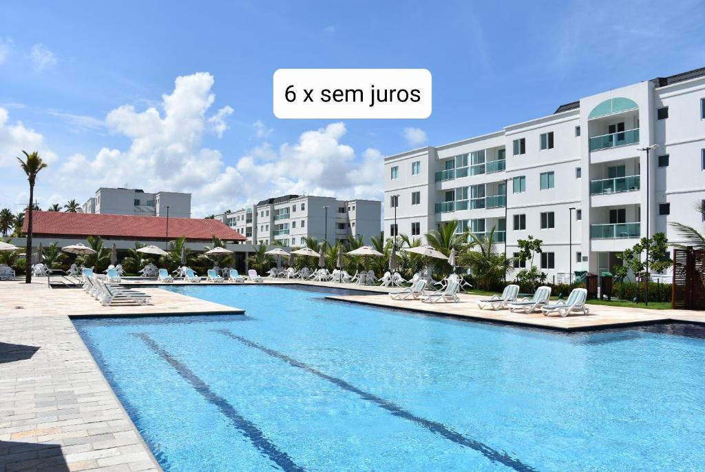 una gran piscina con tumbonas y edificios en Deluxe Palm Aqua, en Porto de Galinhas