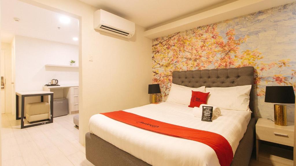 a bedroom with a large bed with a painting on the wall at RedDoorz Plus at La Belle Residences Makati City in Manila