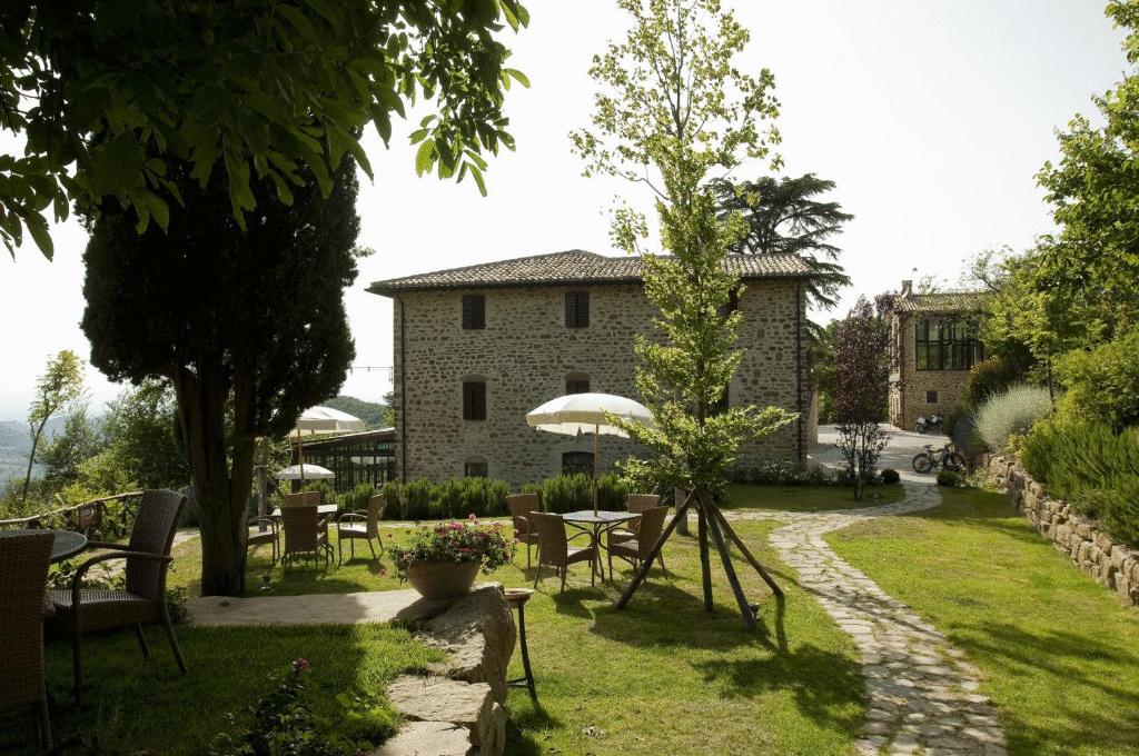 La Tavola Dei Cavalieri في أسيسي: حديقة بها طاولات وكراسي ومبنى