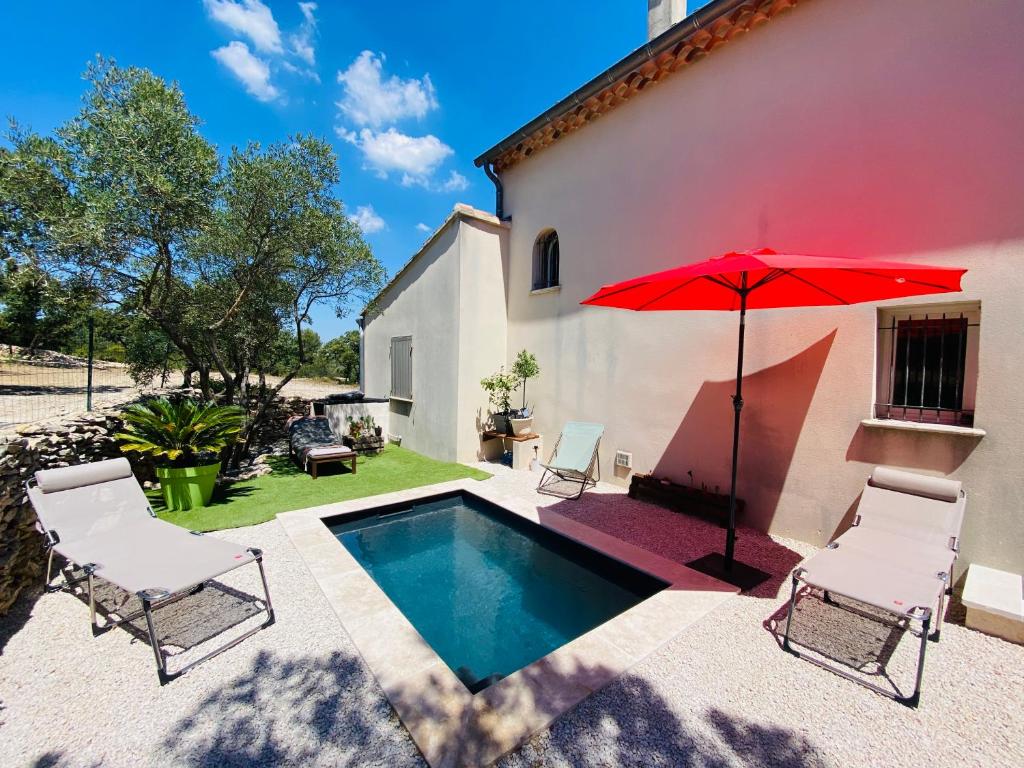 une terrasse avec une piscine, un parasol rouge et des chaises dans l'établissement Studio Tudo Bem, à Villeneuve-lès-Avignon
