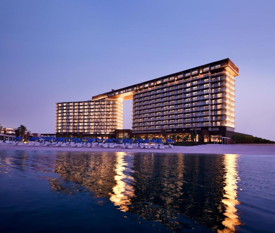 a building on the beach in front of the water at Mövenpick Resort Al Marjan Island in Ras al Khaimah