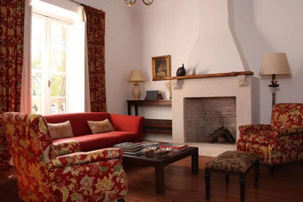 a living room with a red couch and a fireplace at Posada De La Plaza in San Antonio de Areco