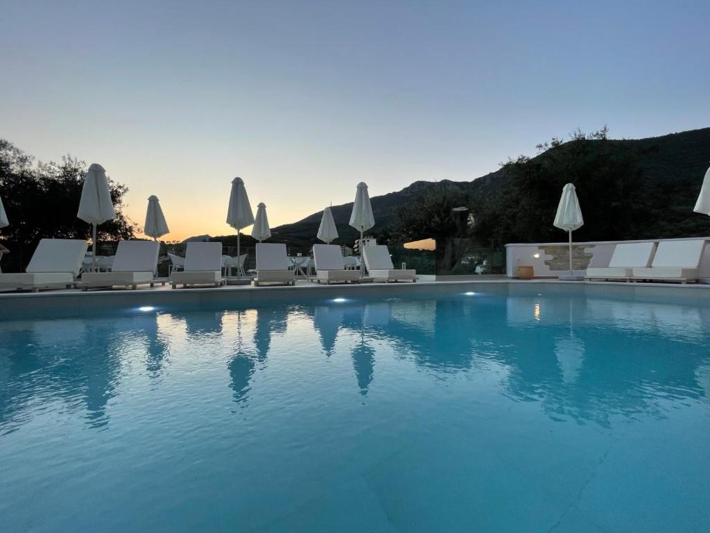 a large swimming pool with white chairs and umbrellas at Gallery Suites Parga in Parga