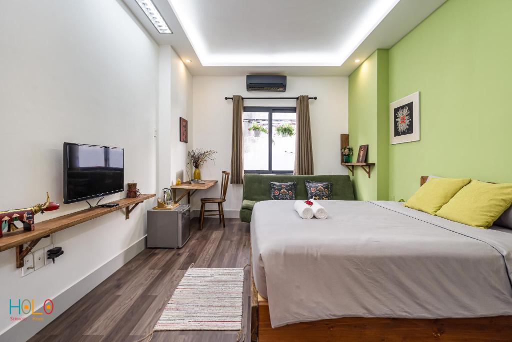 ホーチミン・シティにあるHoLo Central Saigon - Serviced HomeStayの大きなベッドとテレビのある寝室