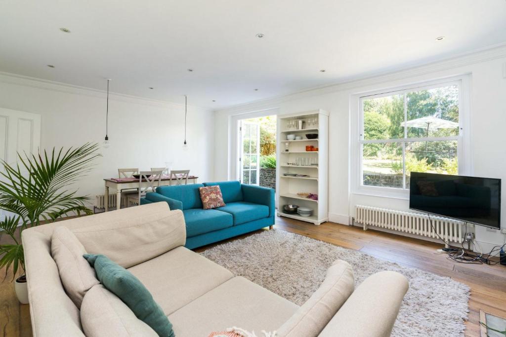 a living room with a blue couch and a tv at Fantastic 3 Bedroom Flat West Hampstead in London