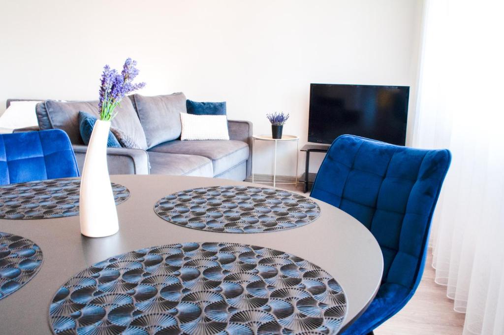 a living room with two tables and blue chairs at Studijos tipo apartamentai Tauragėje in Tauragė