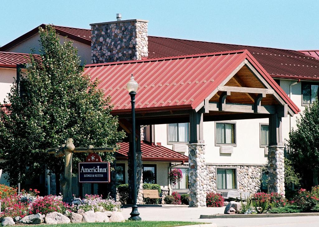 a hotel with a red roof and a sign in front of it at AmericInn by Wyndham Oswego in Oswego