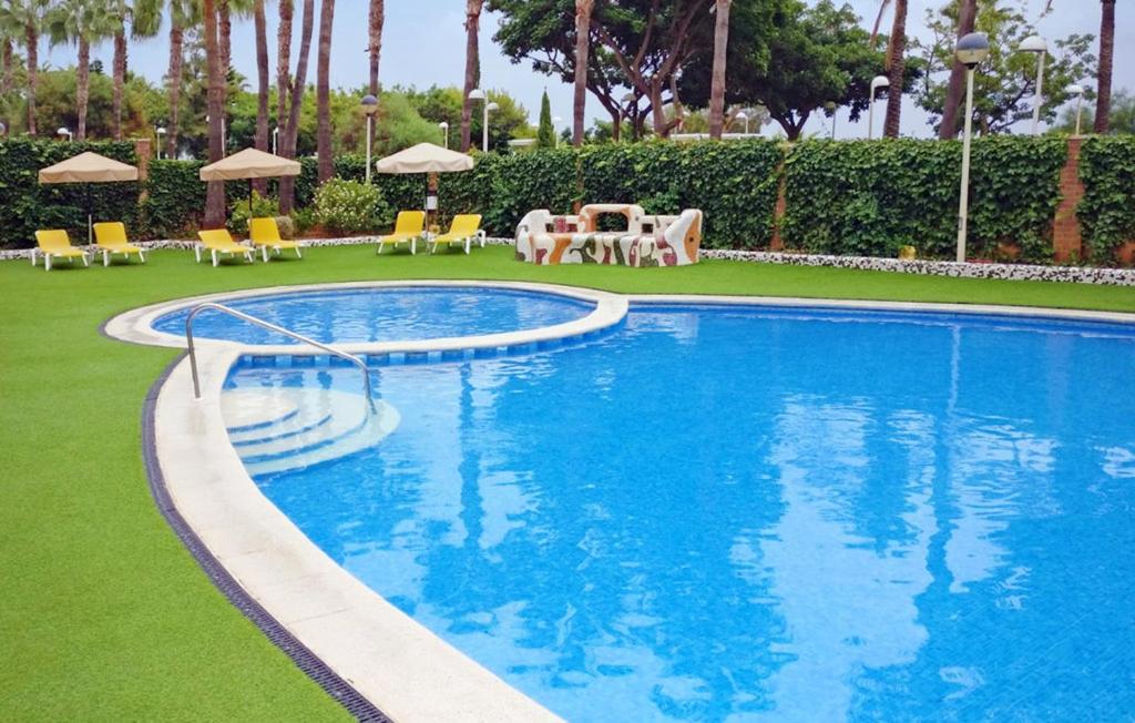 una piscina con sillas y sombrillas en un complejo en Apartamento de 3 dormitorios, 1º línea de playa en Marina d´Or, en Oropesa del Mar