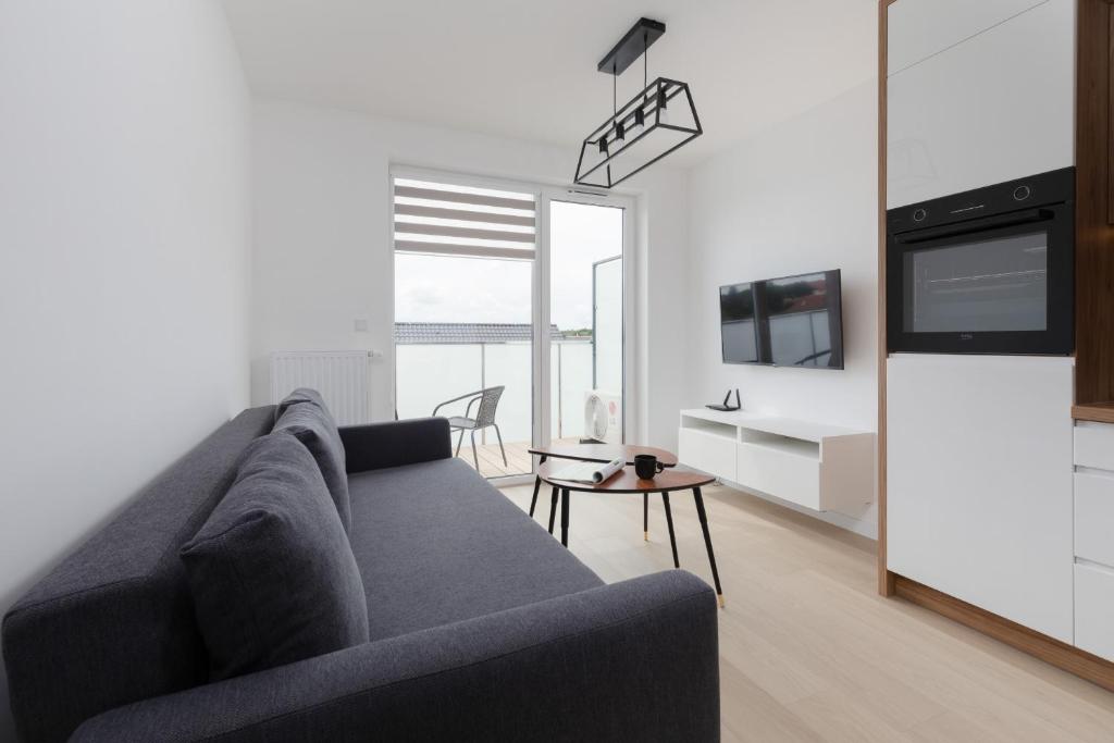 un salon avec un canapé bleu et une table dans l'établissement Posesja Kapitańska Przy Plaży Apartments Grzybowo by Noclegi Renters, à Grzybowo