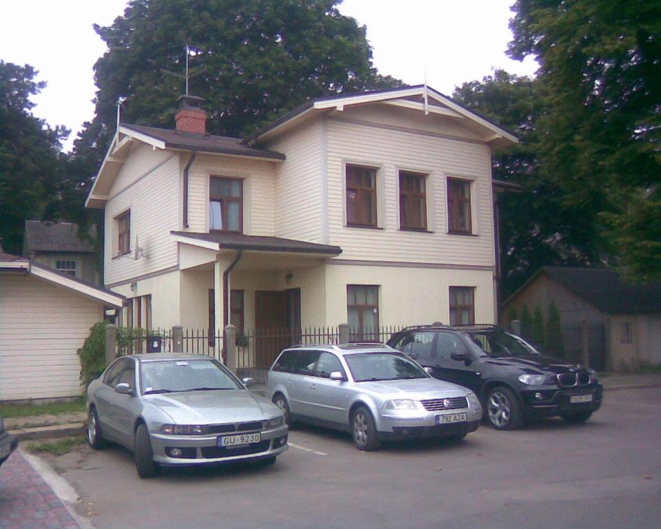 tres autos estacionados en un estacionamiento frente a una casa en Jomas 24, en Jūrmala