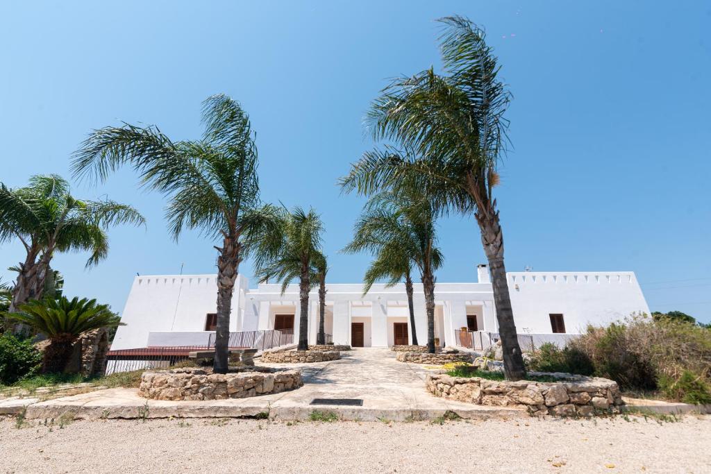 a white building with palm trees in front of it at B&B Agriturismo Tenuta Barone in Gallipoli