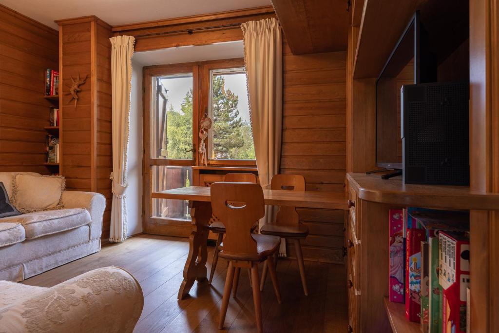 uma sala de estar com uma mesa e uma janela em Casa Scoiattolo em Cortina dʼAmpezzo