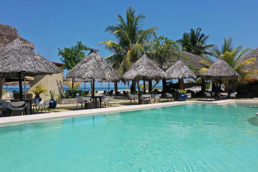 einen Pool in einem Resort mit Stühlen und Sonnenschirmen in der Unterkunft Nosy Be Hotel & Spa in Ambondrona