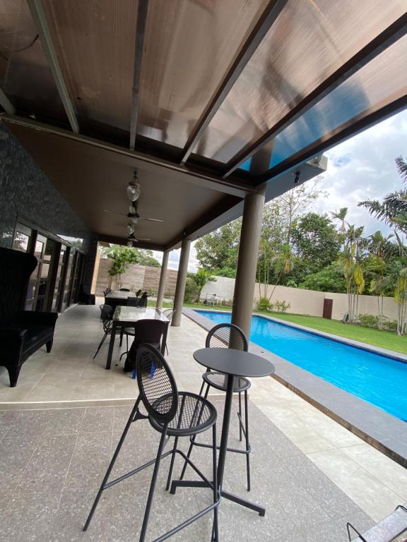 un patio con mesas y sillas y una piscina en Villa Ad Homestay, en Ampang
