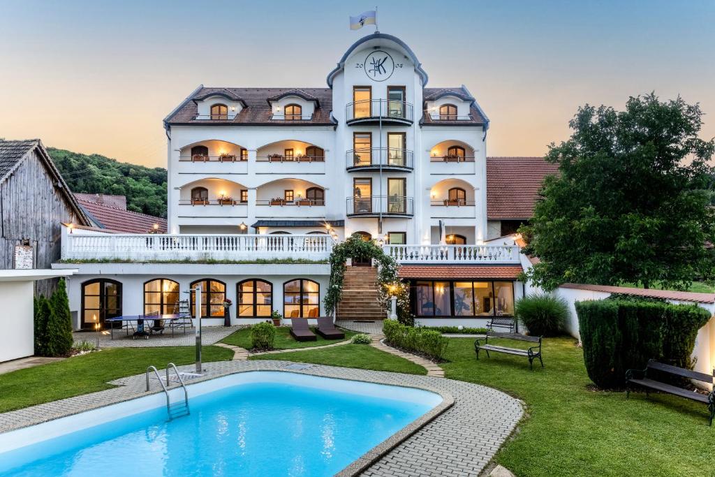 a large white building with a pool in front of it at Genussgasthof & Hotel beim Krutzler in Heiligenbrunn