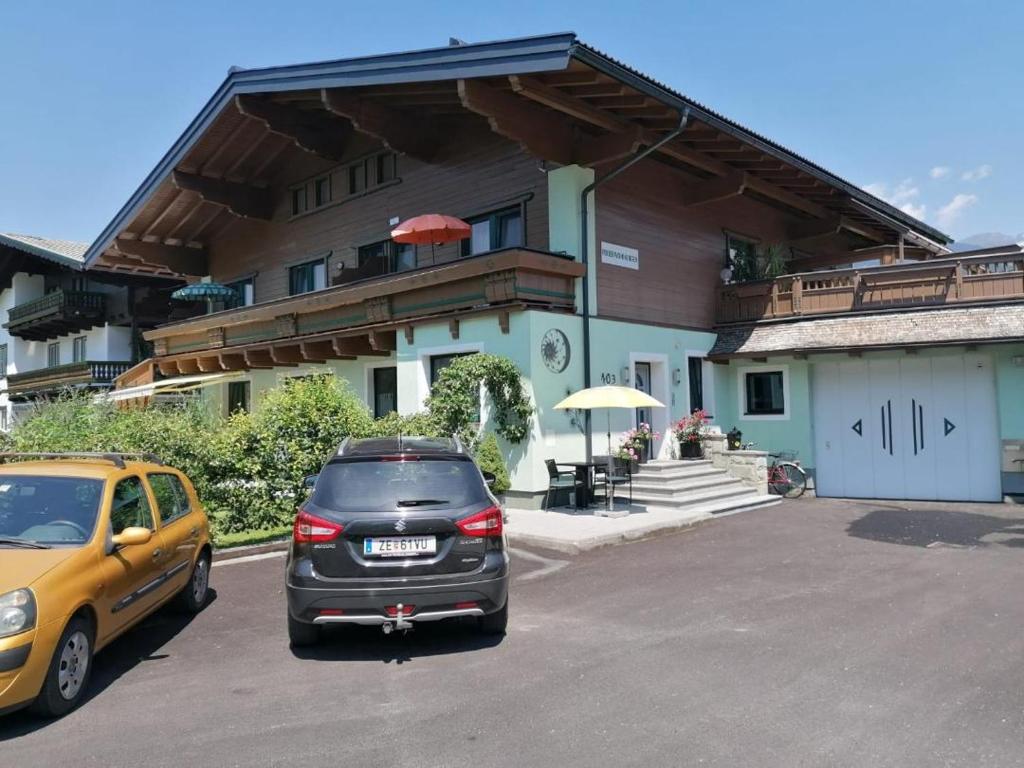 zwei Autos auf einem Parkplatz vor einem Gebäude geparkt in der Unterkunft Ferienwohnung Fred in Hollersbach im Pinzgau