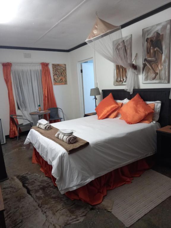 a bedroom with a large bed with orange pillows at Geckos B&B and Self-catering in Coffee Bay