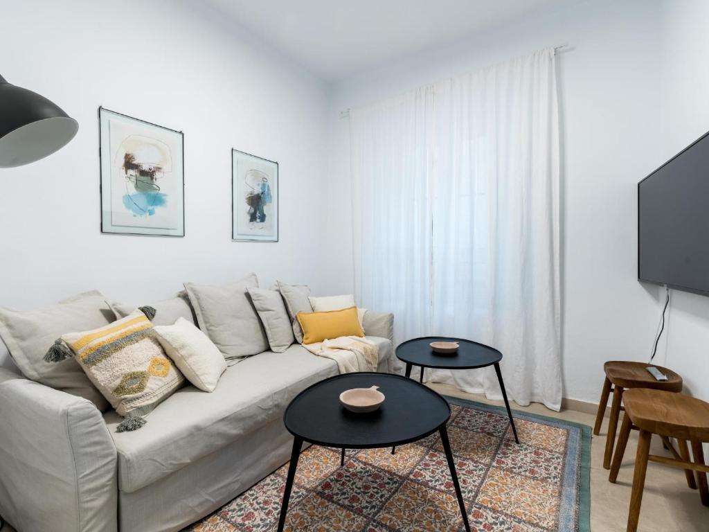 un soggiorno bianco con un divano e due tavoli di Unique Homes La Juderia Parking & Jacuzzi a Siviglia