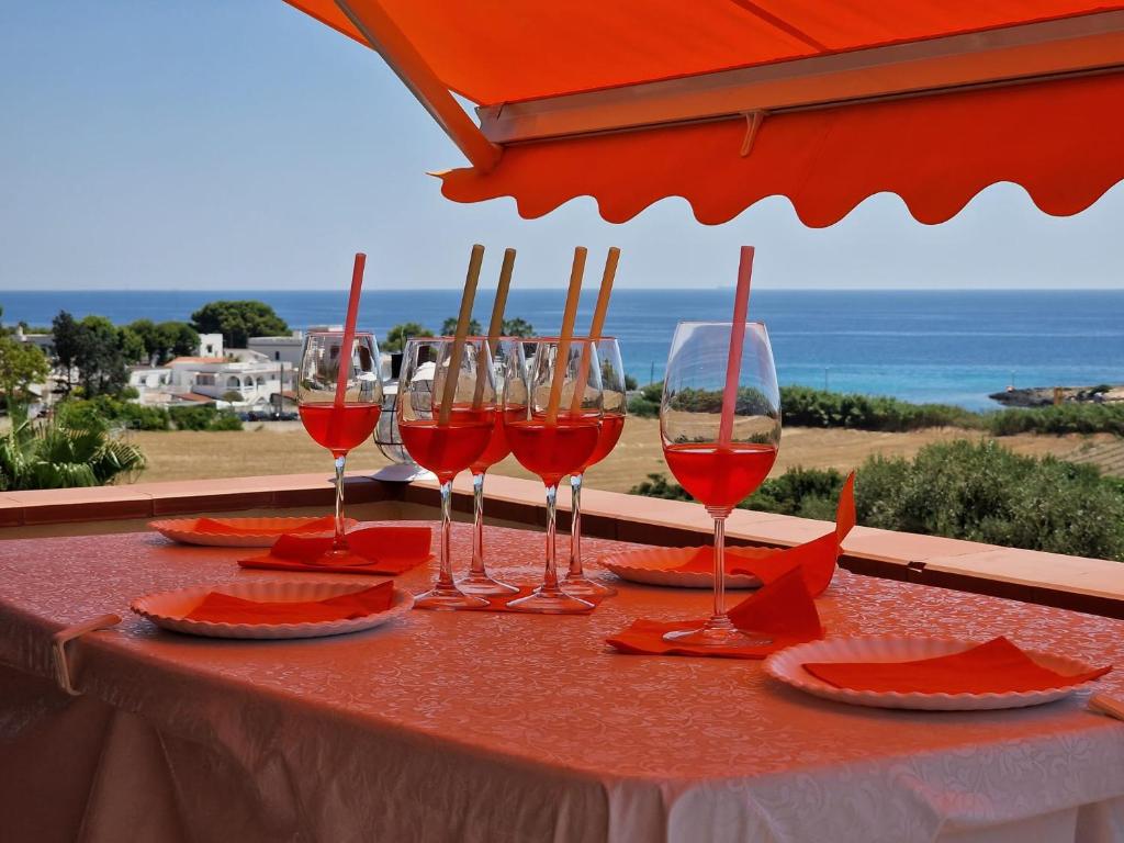four wine glasses sitting on a table with a view of the ocean at BREATHTAKING VIEW OF Salento- in Leporano