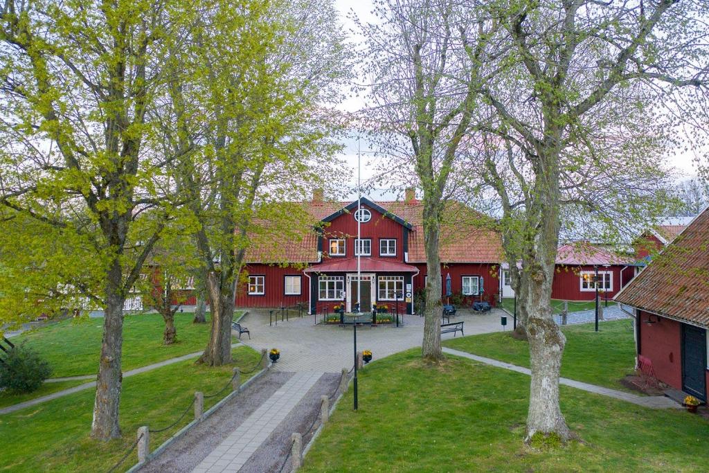 duży czerwony budynek z drzewami przed nim w obiekcie Stufvenäs Gästgifveri w mieście Söderåkra