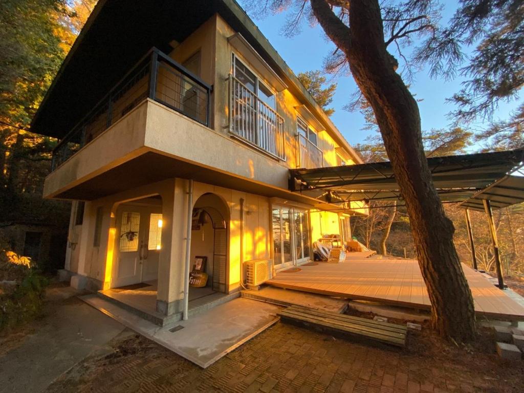 ein großes Haus mit einer Veranda und einem Baum in der Unterkunft Rokko Outdoor Station FOTON in Kōbe
