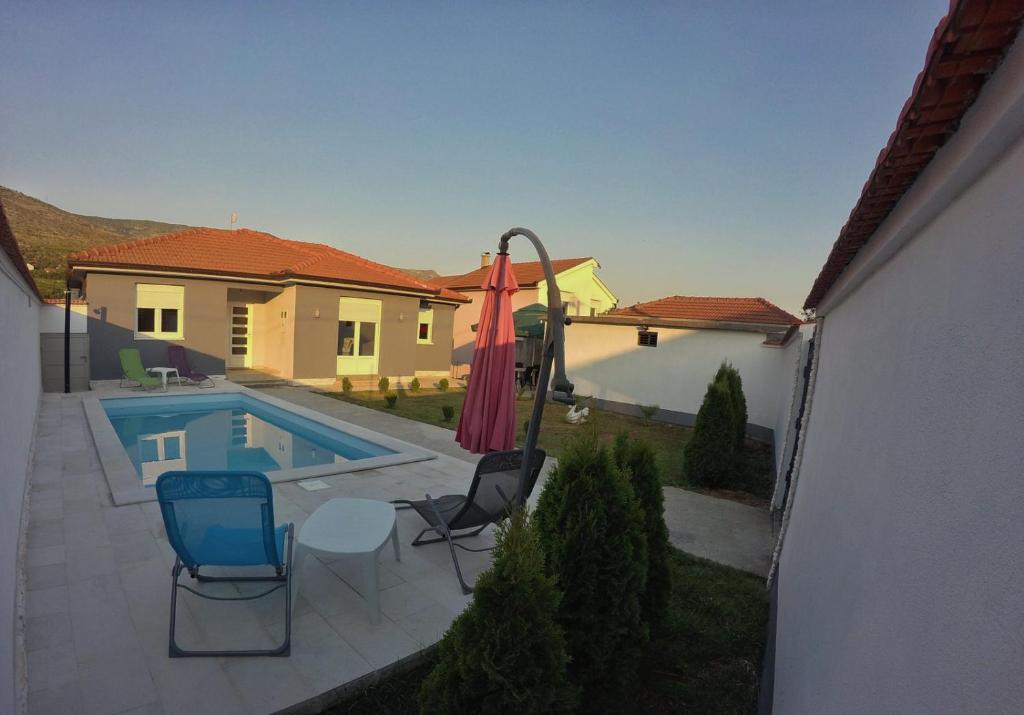 a swimming pool with two chairs and an umbrella at Vila Dolce Vita Mostar in Mostar