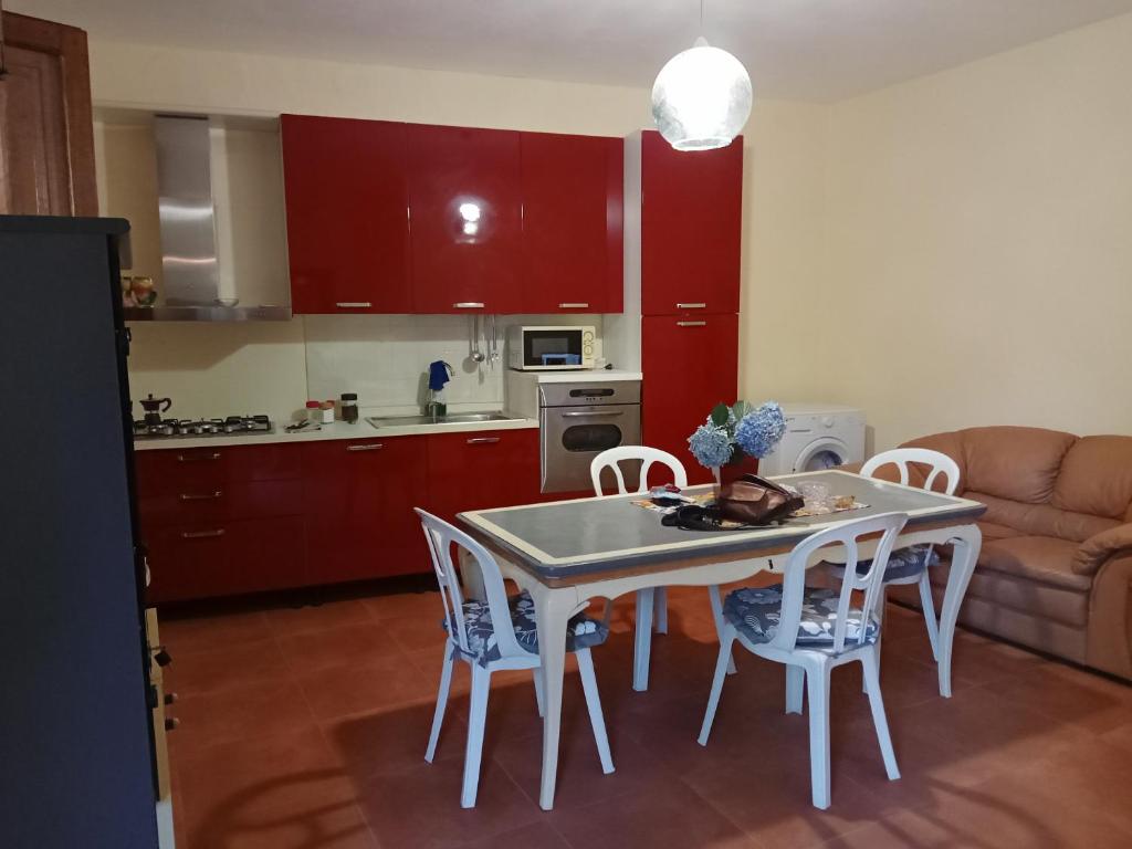 cocina con armarios rojos, mesa y sillas en Capo Vaticano 7km Casa vacanze in Monte Poro en Coccorino