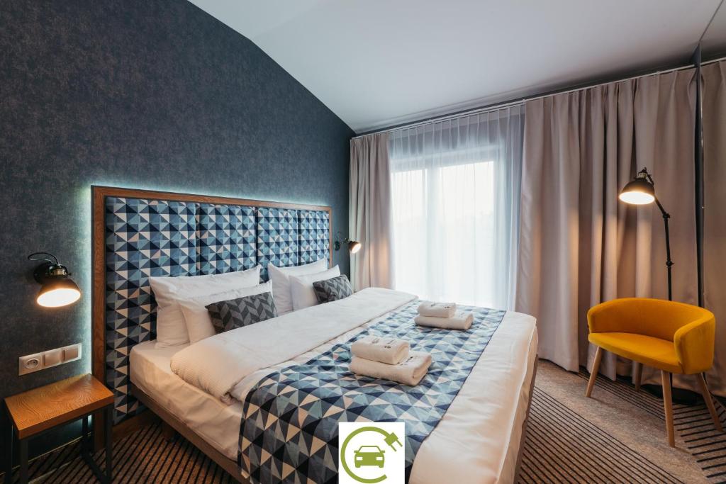 sypialnia z dużym łóżkiem i żółtym krzesłem w obiekcie Avena Boutique Hotel by Artery Hotels w Krakowie