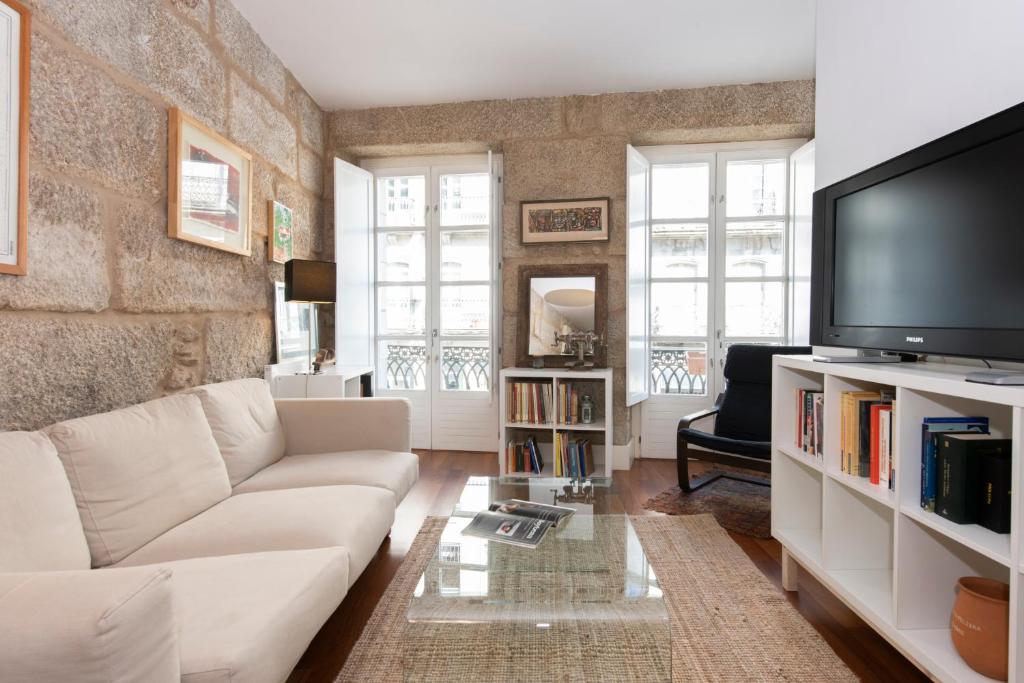 ein Wohnzimmer mit einem weißen Sofa und einem TV in der Unterkunft ELDUAYEN in Vigo