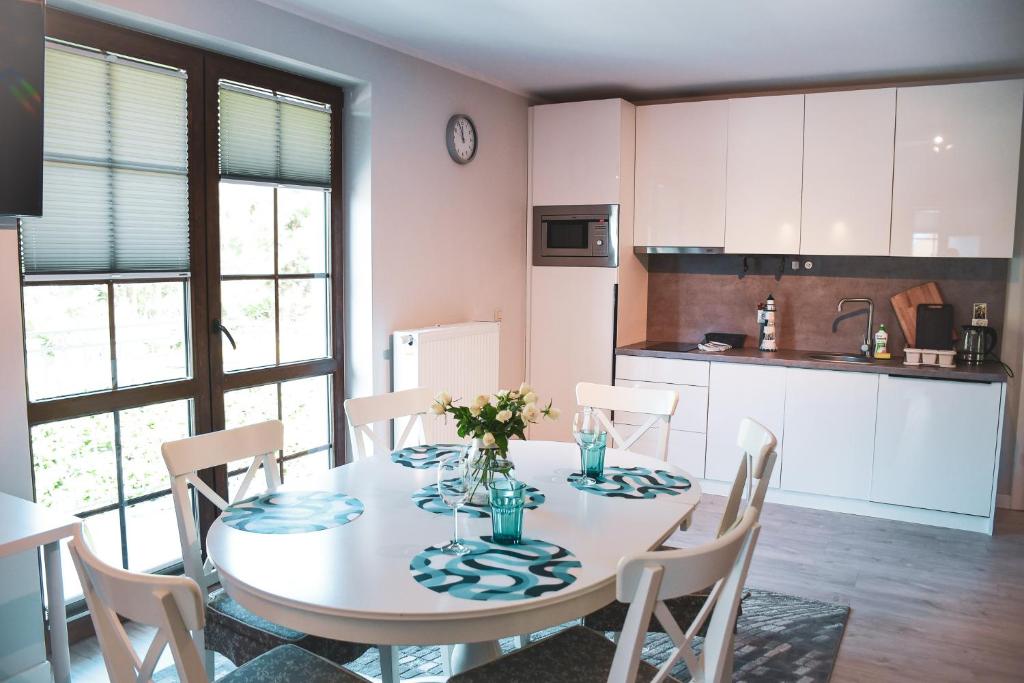 kuchnia z białym stołem z krzesłami, stołem i stołem w obiekcie Apartamenty Liliowa 3 w Dębkach