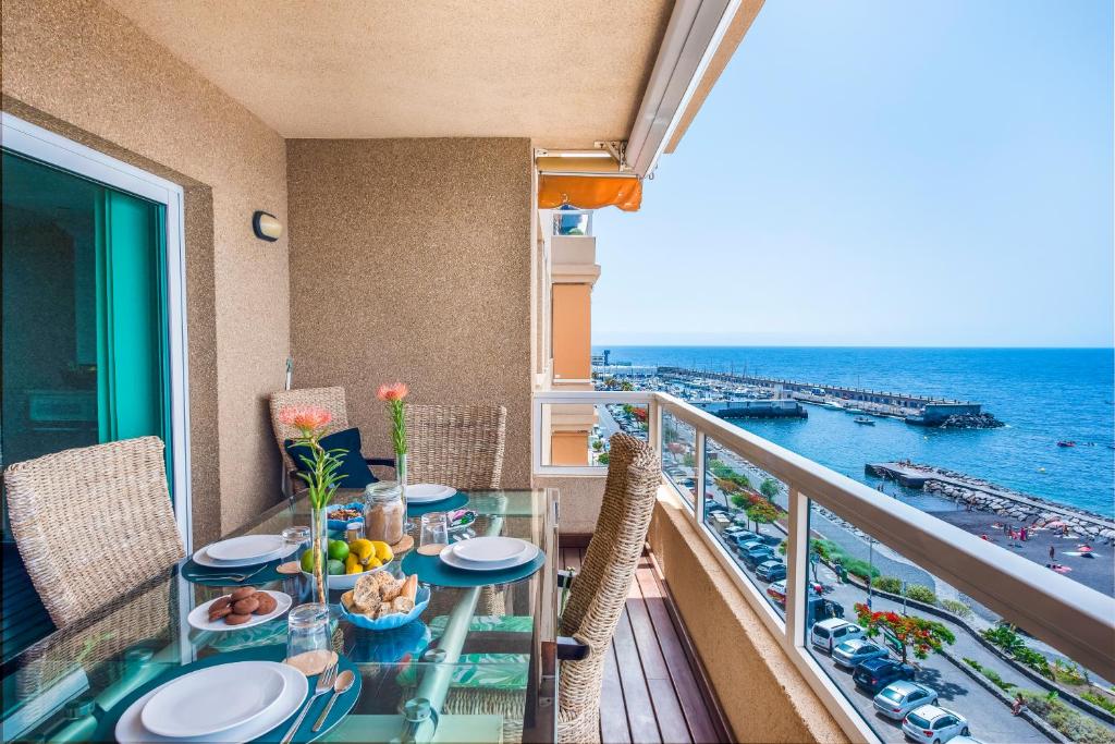 a balcony with a table and chairs and the ocean at Spacious beach apartment with private parking in Radazul