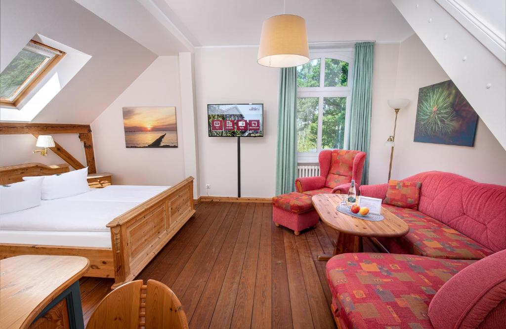 um quarto com uma cama, um sofá e uma mesa em Hotel Schlösschen Sundische Wiese Zingst em Zingst
